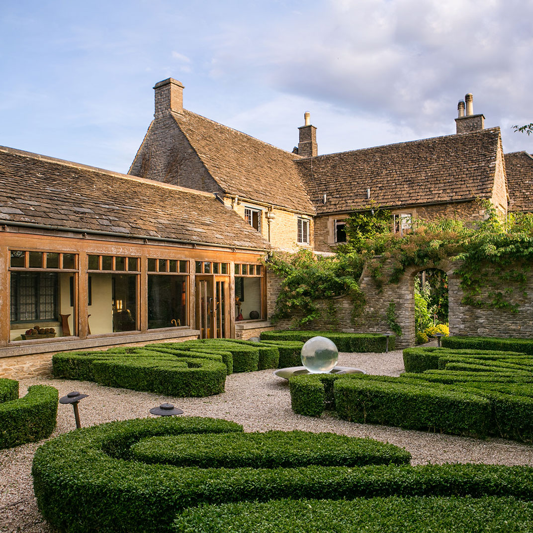 Honey‑colored stone, mullioned windows and clustered roofs give Whatley Manor a classic Cotswolds air. © Whatley Manor