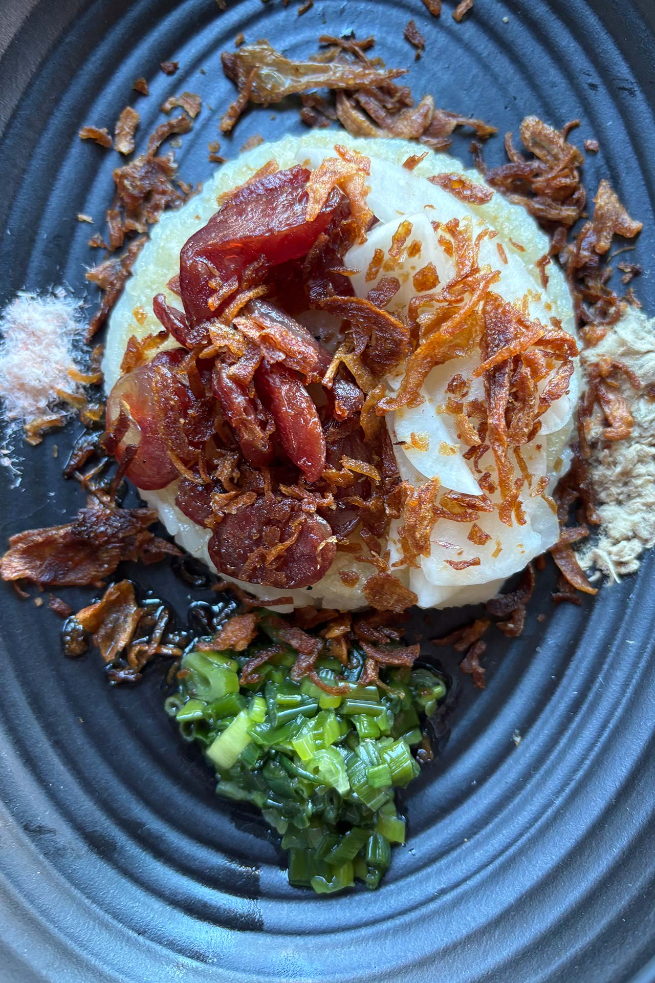 Seared rice cake with lap xuong sausage, fried shallots, pork and shrimp cotton, and scallion oil. ©DanVu Vu/Top Hatters Kitchen