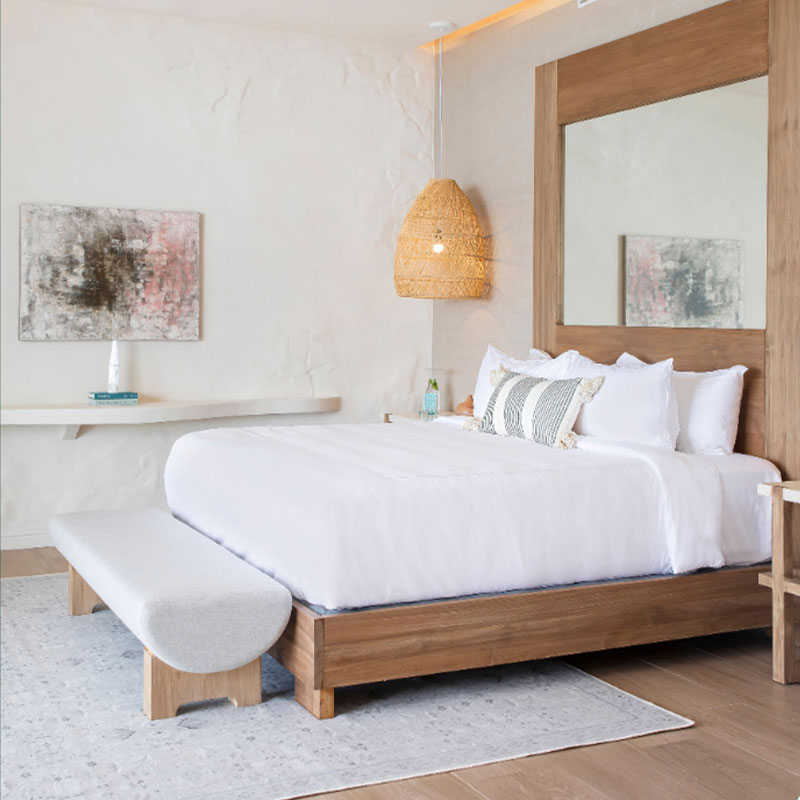 Quarto luminoso com cama de madeira e roupa branca